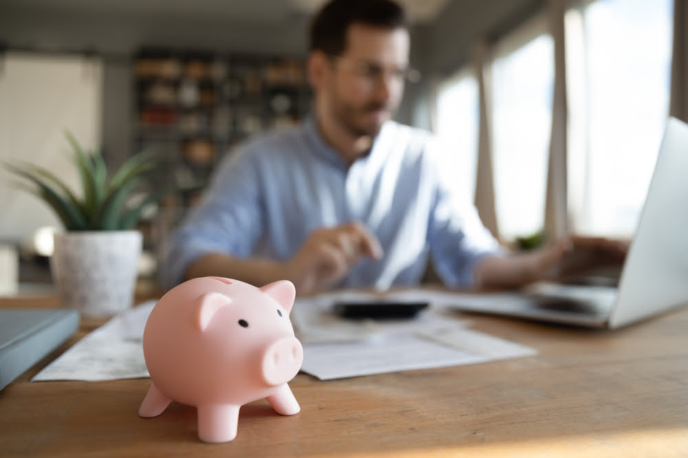 Piggy bank in front of man on laptop